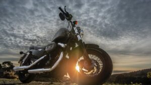 Motorcycle parked outdoors with sunset in the background and dramatic cloudy sky