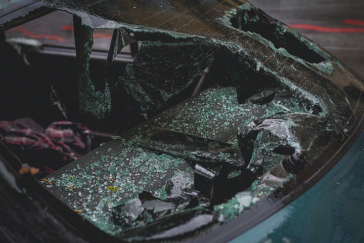 Shattered windshield and crushed roof of a damaged car, with broken glass scattered inside, showing severity of auto accident impact.
