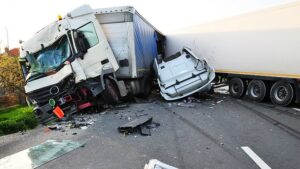 Severe truck accident crushing a white car between two semi-trailers on highway, showing catastrophic collision damage