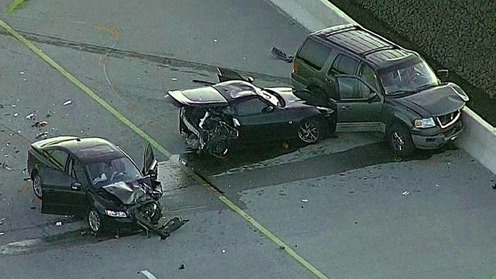 Three-car collision on highway with severe front-end damage, debris on the road, and SUV pinned against the barrier