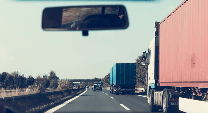 View through windshield of highway with multiple semi-trucks in traffic lanes, emphasizing risks of truck accidents on Texas roads