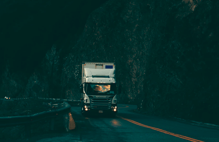 White semi-truck driving on narrow mountain road with steep cliffs, highlighting risks of Texas truck accidents