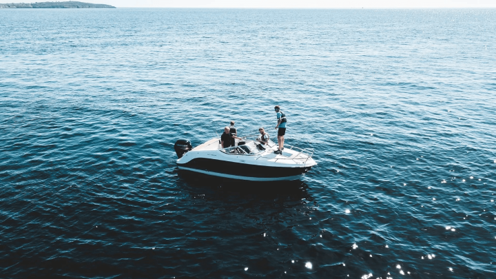 Small motorboat with four people on open water, one standing at the bow, highlighting boating safety and accident risks